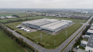 Vue aérienne réaliste d’un centre de données régional français entouré de lignes électriques, d’infrastructures de fibre optique et d’un paysage urbain sobre.